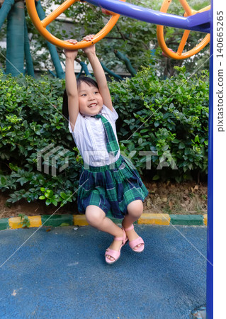 Happy Asian Girl Hanging on Monkey Bars at Playground Happy Asian Girl Hanging on Monkey Bars at Playground 140665265