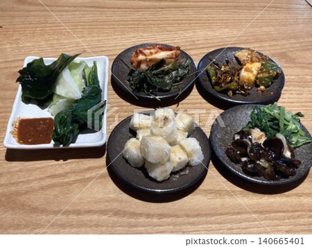 An assortment of colorful banchan, featuring kimchi, seasoned vegetables, pickled radish, and marinated seaweed. These Korean side dishes bring a variety of textures and flavors to the table. An assortment of colorful banchan, featuring kimchi, seasoned vegetables, pickled radish, and marinated seaweed. These Korean side dishes bring a variety of textures and flavors to the table. 140665401