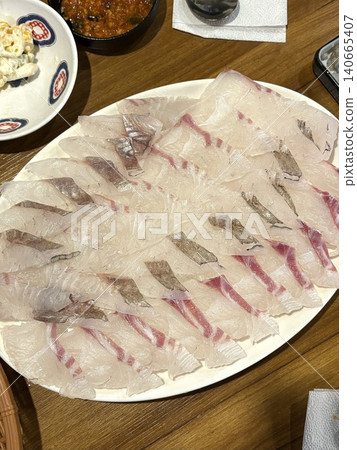 Fresh and delicate sashimi slices, beautifully presented with vibrant colors and perfect cuts. This traditional Japanese delicacy highlights the pure flavors of premium seafood. 140665407