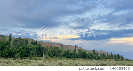 Scenic panoramic view of rolling green hills under a blue cloudy sky Scenic panoramic view of rolling green hills under a blue cloudy sky 140665460