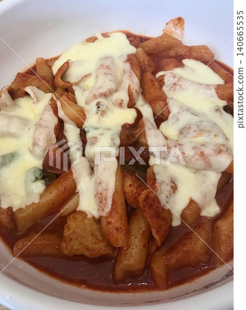 Spicy Korean tteokbokki with chewy rice cakes in a vibrant red sauce, topped with sesame seeds and green onions. A popular street food known for its addictive flavor and satisfying texture. 140665535