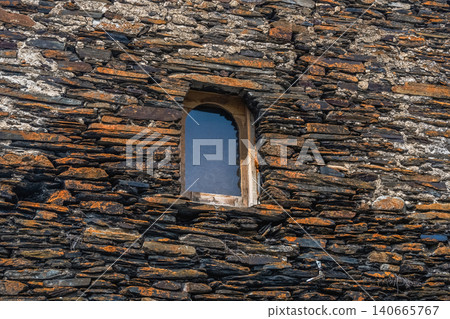 Ancient stone wall, weathered and textured with small arched window Ancient stone wall, weathered and textured with small arched window 140665767