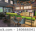 Modern coffee shop interior featuring a vibrant illuminated green service counter, stylish wooden bar. 140666041