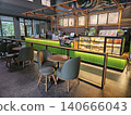 Modern coffee shop interior featuring a vibrant illuminated green service counter, stylish wooden bar. 140666043