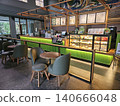Modern coffee shop interior featuring a vibrant illuminated green service counter, stylish wooden bar. 140666048