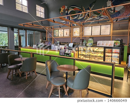 Modern coffee shop interior featuring a vibrant illuminated green service counter, stylish wooden bar. 140666049