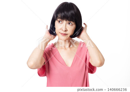 一位留著波波頭、身穿粉紅色短袖針織衫的中年婦女正在整理頭髮。 140666236