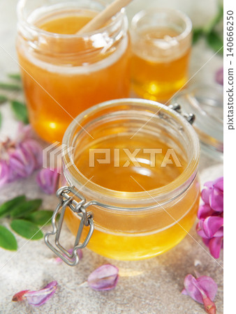 Acacia honey in glass jar surrounded by flowers Acacia honey in glass jar surrounded by flowers 140666250