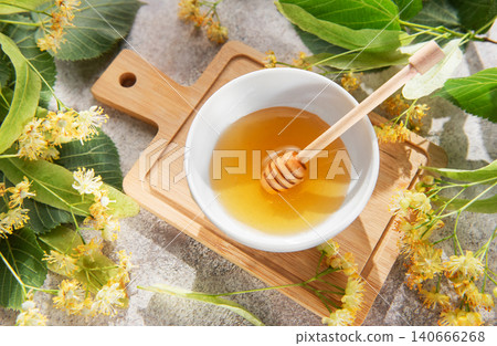 Linden honey in bowl with dipper and flowers Linden honey in bowl with dipper and flowers 140666268