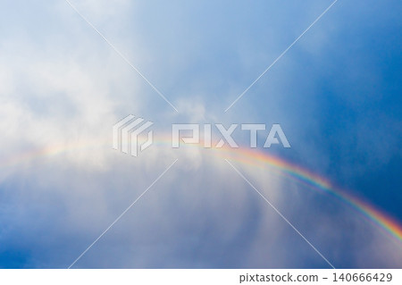A vibrant rainbow arcs across a moody blue sky 140666429