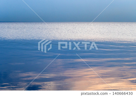 Serene blue ocean horizon with gentle ripples and soft sunset 140666430