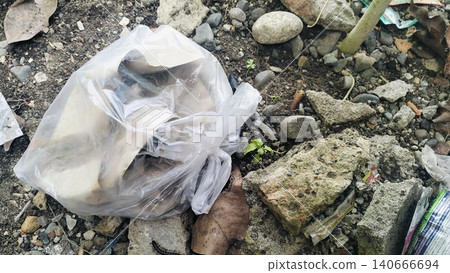 Plastic bag filled with garbage abandoned on dirty soil ground. Plastic bag filled with garbage abandoned on dirty soil ground. 140666694