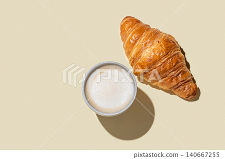 Cup of cappuccino coffee and croissant on a yellow isolated background Cup of cappuccino coffee and croissant on a yellow isolated background 140667255