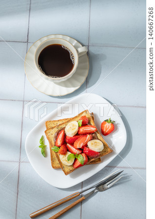 Toasted bread with chocolate cream, strawberries, and banana on a plate on a tile  background 140667268