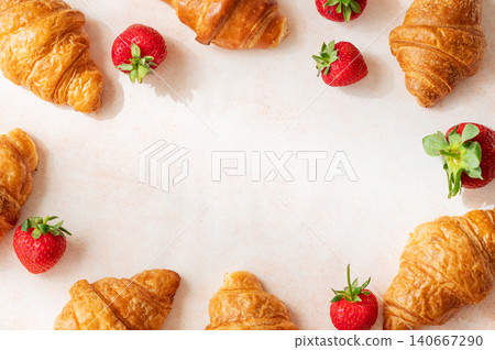 Frame of freshly baked croissants and strawberries on a bright textured background. Frame of freshly baked croissants and strawberries on a bright textured background. 140667290