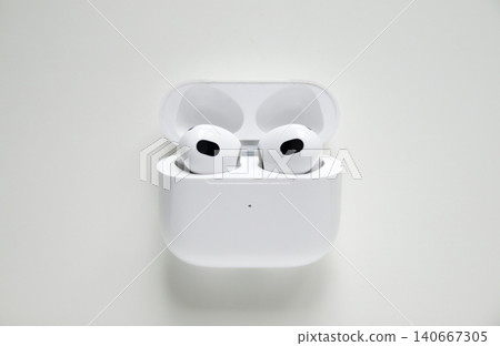 Wireless earphones in charging case open on white background. Top view of white bluetooth earbuds, modern technology gadgets, audio electronics and minimalist lifestyle concept 140667305