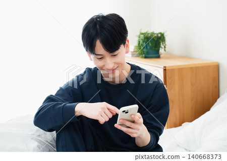 年輕人在床上觀看智能手機 140668373