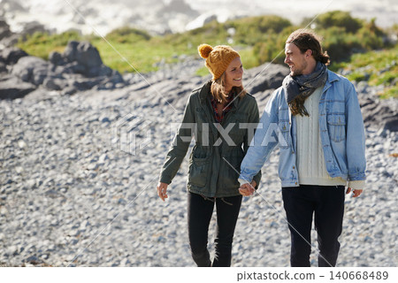 Walking, holding hands and beach with couple, nature and happiness with vacation and romance. Seaside, relationship and man with woman or marriage with holiday for honeymoon and adventure with smile 140668489