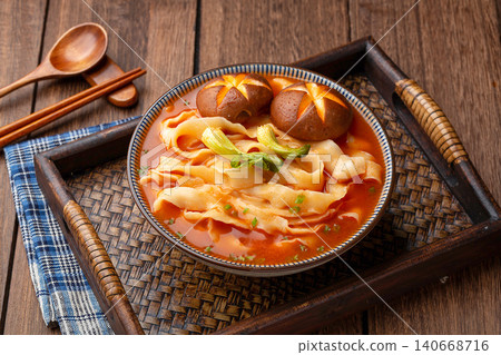 Chinese traditional knife-cut noodles in rich tomato soup with shiitake mushrooms on a wooden tray. Chinese traditional knife-cut noodles in rich tomato soup with shiitake mushrooms on a wooden tray. 140668716
