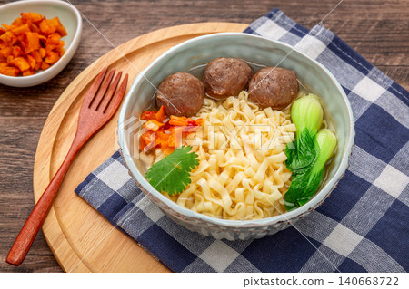 Appetizing curly egg noodles with juicy beef meatballs and bok choy on a wooden platter. Appetizing curly egg noodles with juicy beef meatballs and bok choy on a wooden platter. 140668722