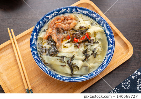 Henan traditional Hutu noodle soup with preserved sesame leaves and shredded pork on a wooden platter. 140668727
