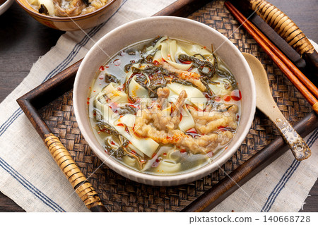 Henan traditional Hutu noodle soup with preserved sesame leaves and shredded pork on a wooden platter. 140668728