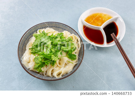 Refreshing dry mixed flat noodles topped with fresh minced garlic sauce and cucumber shreds 140668733
