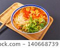 Classic Chinese tomato and egg noodle soup garnished with fresh green vegetables in a blue ceramic bowl 140668739