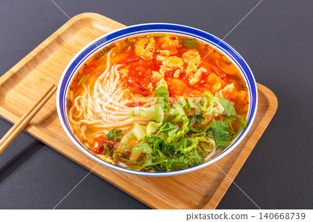 Classic Chinese tomato and egg noodle soup garnished with fresh green vegetables in a blue ceramic bowl Classic Chinese tomato and egg noodle soup garnished with fresh green vegetables in a blue ceramic bowl 140668739