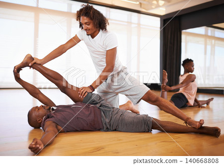 Dancer, instructor and stretching with helping in class for warm up, fitness or muscle health on floor. Men, coach and support for dancing, workout or ready to start with legs in studio for exercise Dancer, instructor and stretching with helping in class for warm up, fitness or muscle health on floor. Men, coach and support for dancing, workout or ready to start with legs in studio for exercise 140668808