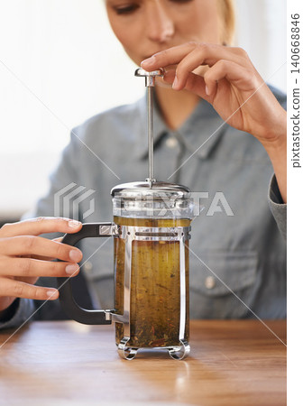 Woman, closeup or herbal tea to relax in home and warm beverage of herbs mixture in plunger for health. Herbalist, drink or creative idea for dry leaves and wellness for detox liquid on kitchen table Woman, closeup or herbal tea to relax in home and warm beverage of herbs mixture in plunger for health. Herbalist, drink or creative idea for dry leaves and wellness for detox liquid on kitchen table 140668846