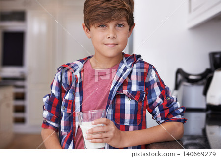 Portrait, milk and boy child in kitchen of home in morning for calcium, drink or nutrition for growth. Dairy, glass and health with young teen kid in apartment, drinking fresh beverage for vitamins Portrait, milk and boy child in kitchen of home in morning for calcium, drink or nutrition for growth. Dairy, glass and health with young teen kid in apartment, drinking fresh beverage for vitamins 140669279