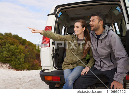 Couple, car and pointing on road trip with relax for adventure, vacation and sightseeing with happiness in countryside. Woman, men or travel in vehicle for holiday journey, tourism or outdoor scenery 140669322