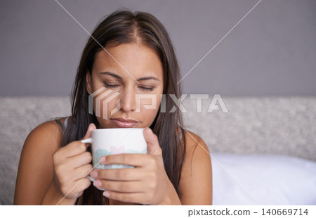 Woman, eyes closed or coffee in bed to wake up in peace on morning routine as mental health. Tired, sleepy or female person for tea, warm or comfort as soothing, self care or stress relief in bedroom 140669714