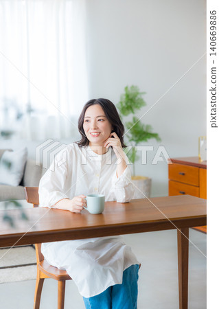 Young woman drinking coffee in the living room Young woman drinking coffee in the living room 140669886