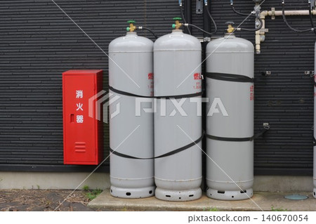 LP gas cylinders and a red fire extinguisher box installed on the exterior wall of the building. LP gas cylinders and a red fire extinguisher box installed on the exterior wall of the building. 140670054