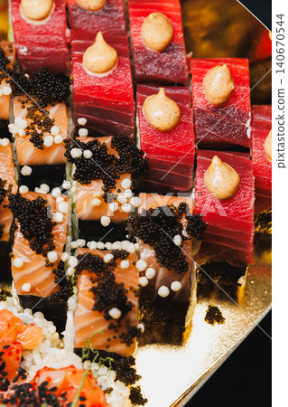 Sushi platter with assorted cuts of raw fish, caviar, and sauce served on a gold tray during a dinner event in a restaurant 140670544