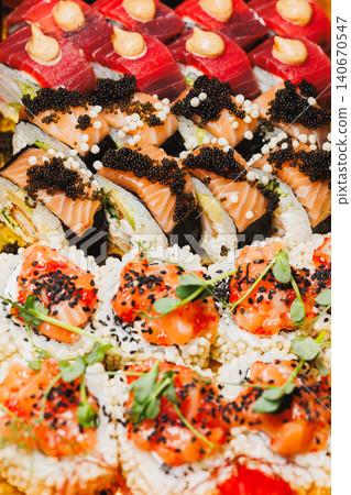 Sushi rolls and sashimi arranged on a platter for serving at a restaurant during dinner time Sushi rolls and sashimi arranged on a platter for serving at a restaurant during dinner time 140670547