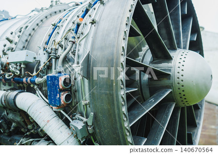 Close view of a large aircraft jet engine with complex components, taken at an airport during daylight Close view of a large aircraft jet engine with complex components, taken at an airport during daylight 140670564