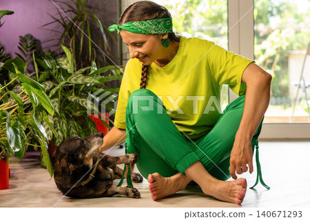Woman Playing With Small Dog In Plant Filled Home Woman Playing With Small Dog In Plant Filled Home 140671293