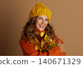 Smiling Woman in Autumn Scarf and Hat with Leaves 140671329