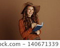 Smiling Woman Making Notes in Blue Notebook 140671339