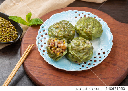 steamed sticky whole grain buns with sweet red bean filling on a blue ceramic plate 140671660
