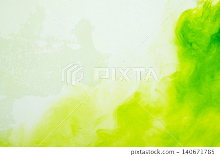 A vibrant abstract background featuring bright green and lime yellow ink or watercolor paint diffusing and swirling smoothly on a light textured canvas surface 140671785