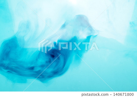 Abstract close-up of vibrant blue ink diffusing and swirling gracefully in clean water, creating soft smoke-like patterns against a light cyan background Abstract close-up of vibrant blue ink diffusing and swirling gracefully in clean water, creating soft smoke-like patterns against a light cyan background 140671800