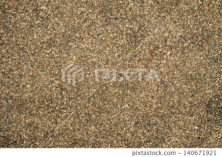 Continuous outdoor surface covered with medium-grain yellow-brown gravel mix and sand aggregate, daylight Continuous outdoor surface covered with medium-grain yellow-brown gravel mix and sand aggregate, daylight 140671921