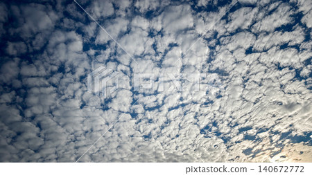 Expansive view of a cloudy sky filled with textured white clouds against a deep blue background, showcasing a serene and tranquil atmosphere in nature 140672772