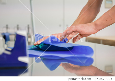 Healthcare worker hands carefully folding blue protective sterilization paper around medical equipment in a sterile hospital room to emphasize clinical safety and hygiene protocols 140672993
