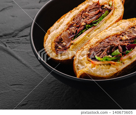 Pulled pork sandwich halves in bowl on dark background Pulled pork sandwich halves in bowl on dark background 140673605