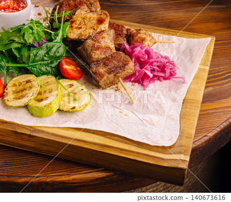 Grilled pork kebab skewers served with fresh salad, vegetables, pickled onions Grilled pork kebab skewers served with fresh salad, vegetables, pickled onions 140673616